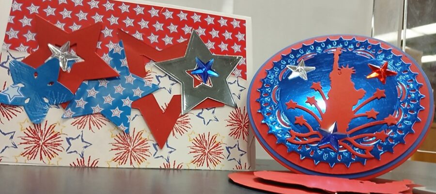 Example of cards that will be crafted. One card is red, white, and blue stars with fireworks in the background. The other card is circular with stars and the statue of liberty.