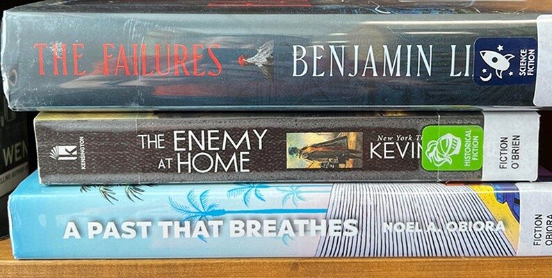 An example of book spine poetry with 3 stacked books whose titles read "The failures, The Enemy at Home, A Past That Breathes"
